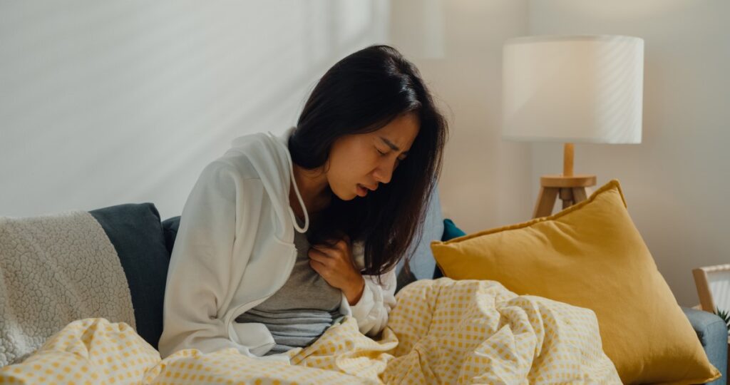 A young woman experiencing chest pain in a loungeroom setting