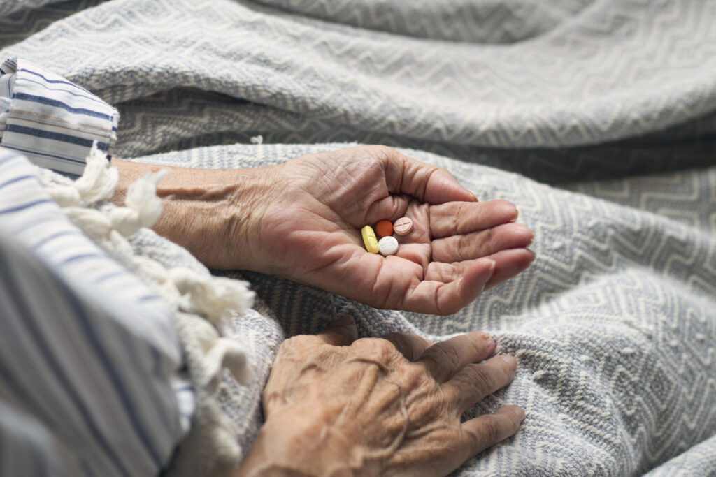 Old woman holding medicinal tablets.
